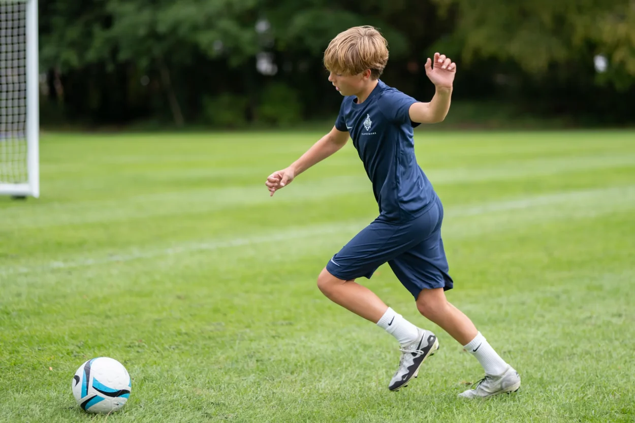 A Clayesmore academy player training with a football on the school grounds